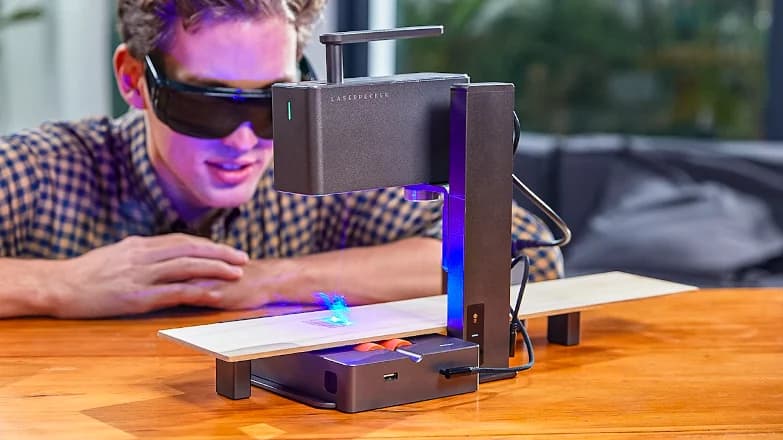 Engraving a wooden blank, blue laser firing, safety goggles on